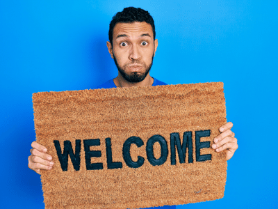 man holding doormat saying welcome